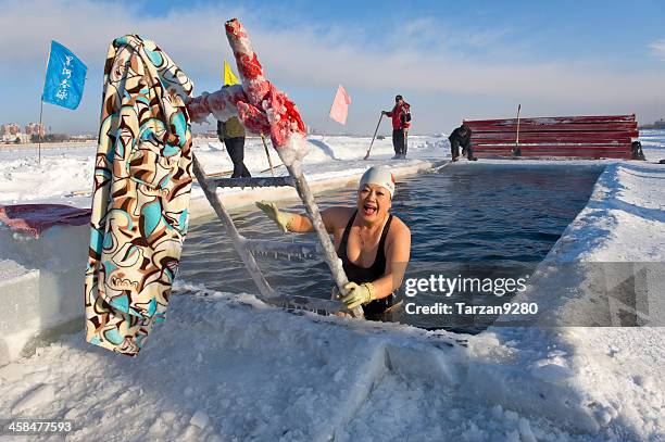 female winter swimmer coming out pool from ice - winter swimming stock pictures, royalty-free photos & images