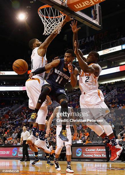 Mike Conley of the Memphis Grizzlies makes a leaping pass inbetween Markieff Morris and Eric Bledsoe of the Phoenix Suns during the second half of...
