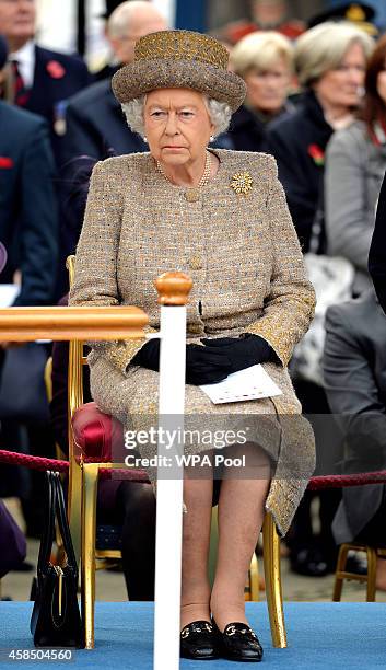 Queen Elizabeth II sits before she places a wreath of poppies at the new Flanders Field Memorial outside the Guards Chapel on November 6, 2014 in...