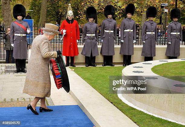 Queen Elizabeth II places a wreath of poppies at the new Flanders Field Memorial outside the Guards Chapel on November 6, 2014 in London, England.