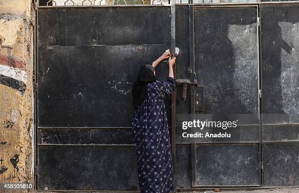 An Egyptian woman warden closes the main gate of a primary school, where nearly 2 thousand students get education, at the end of the day in Baragil...