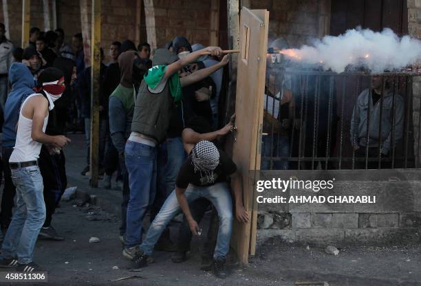 Masked Palestinian youths use doors as shield during clashes with Israeli security forces in the Palestinian refugee camp of Shuafat in east...