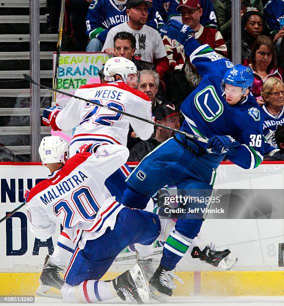 Dale Weise and Manny Malhotra of the Montreal Canadiens check Jannik Hansen of the Vancouver Canucks during their NHL game at Rogers Arena October...