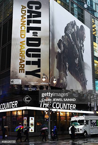 People walk past a billboard advertising the latest installment of "Call of Duty" video game near Times Square in New York on November 6, 2014. The...