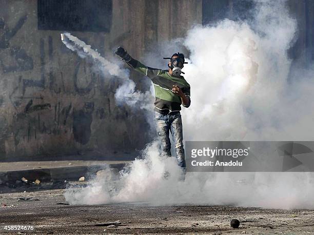 Palestinian protester throws a stone during clashes with Israeli police at Shuafat refugee camp after a Palestinian rammed his vehicle into a crowd...
