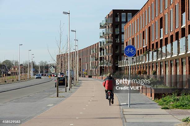 street with suburban houses and a cyclist in leidsche rijn - utrecht city stock pictures, royalty-free photos & images