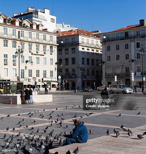 alter mann fütterung von tauben in figueira square in lissabon - praca de figueria stock-fotos und bilder