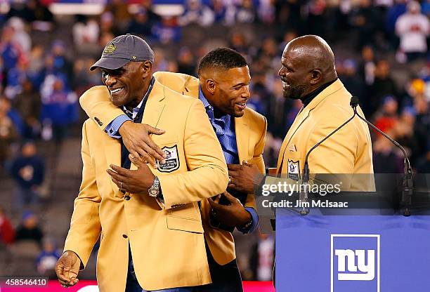Hall of Famers Harry Carson , Michael Strahan and Lawrence Taylor have a laugh during a halftime ceremony of a game between the New York Giants and...