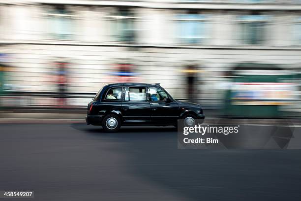 traditional black taxi cab speeding down street in london - london taxi stock pictures, royalty-free photos & images