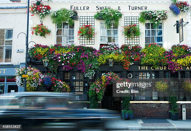taxi cab driving past traditional london pub decorated with flowers - notting hill street stock pictures, royalty-free photos & images