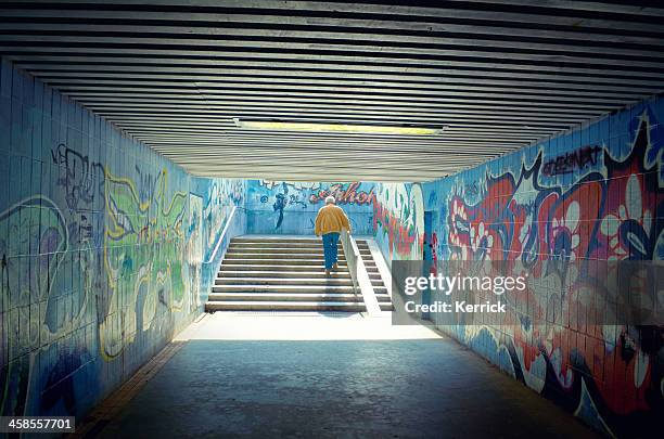 man walking at a passage underground with way intoto light - underpass stock pictures, royalty-free photos & images