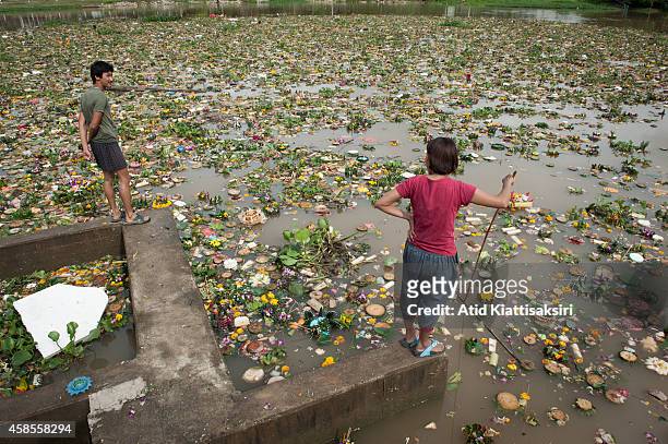 Thais stand on a floodgate to find valuables from krathongs in the Ping river during Loy Krathong Festival in Chiang Mai. People place money along...