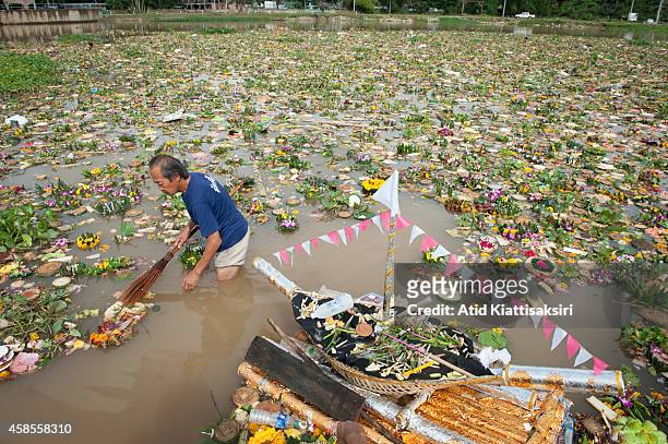 An elderly Thai man finds valuables from thousands of krathongs on the Ping river during Loy Krathong Festival in Chiang Mai. People place money...