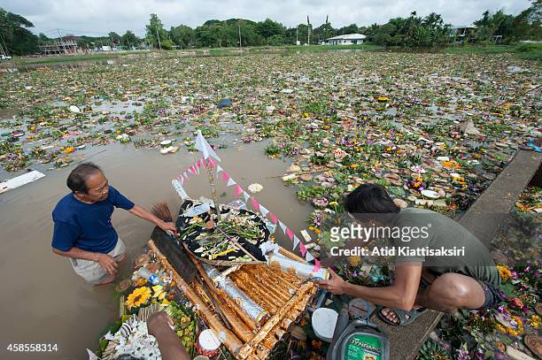 Thai men find valuables from a big krathong on the Ping river during Loy Krathong Festival in Chiang Mai. People place money along with candles and...