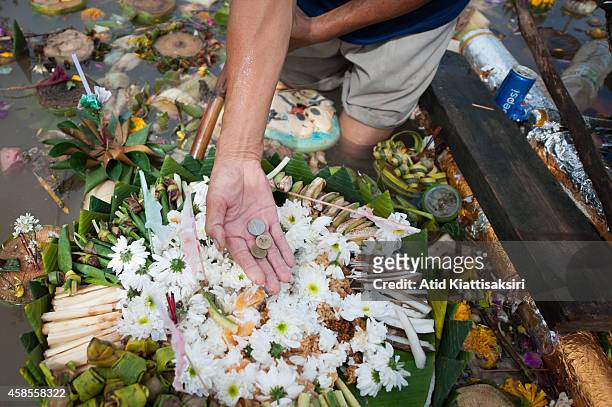 Thai man shows some Thai Baht coins that he found on a krathong that was floating on the Ping river during Loy Krathong Festival in Chiang Mai....