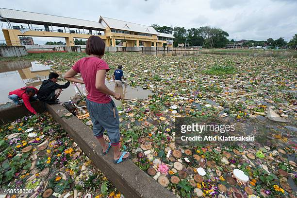 Thais find valuables from thousands of Krathongs at a floodgate of the Ping river during Loy Krathong Festival. People place money along with candles...