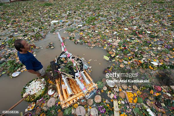 An elderly Thai man finds valuables from thousands of krathongs on the Ping river during Loy Krathong Festival in Chiang Mai. People place money...