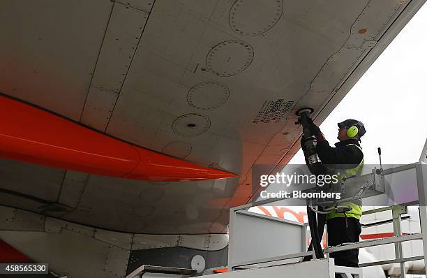 Member of the ground crew connects a fuel house to the wing of an Airbus Group NV aircraft, operated by EasyJet Plc, during the refueling process...