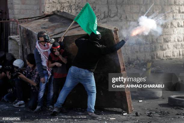 Palestinians and photographers take cover behind a container during clashes with Israeli security forces in the Palestinian refugee camp of Shuafat...