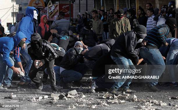 Masked Palestinian youths prepare to throw stones during clashes with Israeli security forces in the Palestinian refugee camp of Shuafat in east...