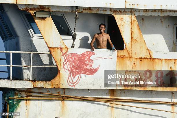 Crew member on a boat in waters near Chichijima island smiles at a passing boat as they appear to be coaching coral on November 2, 2014 in Ogasawara,...