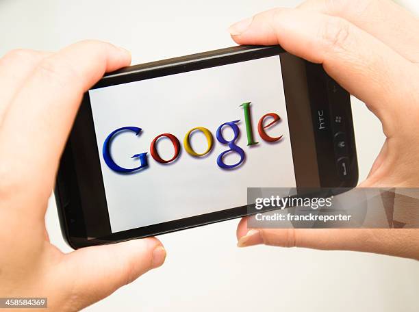mano che tiene il telefono intelligente con google logo - www google image com foto e immagini stock