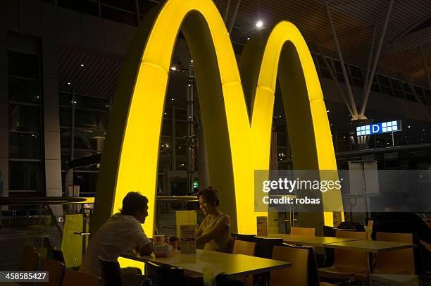 smiling asian couple eating in mcdonalds restaurant - mcdonalds 個照片及圖片檔