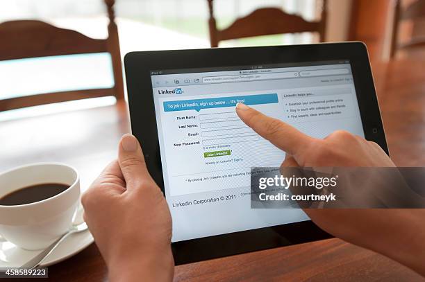 mulher a segurar um ipad mostrando o linkedin ecrã de início de sessão. - linkedin imagens e fotografias de stock