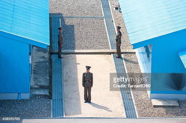 north korean soldiers standing between blue buildings - panmunjom stock pictures, royalty-free photos & images