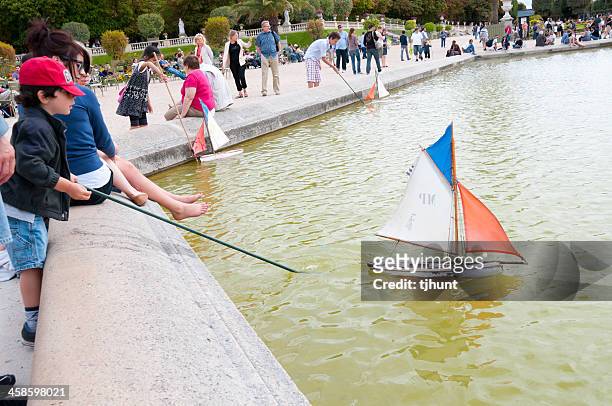 garçons pousser un bateau miniature sur le jardin du luxembourg, paris - jardin du luxembourg photos et images de collection