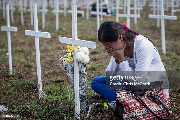 Woman cries at the cross of a loved one at the mass grave on the grounds of the Holy Cross Memorial Garden on November 8, 2014 in Tacloban, Leyte,...