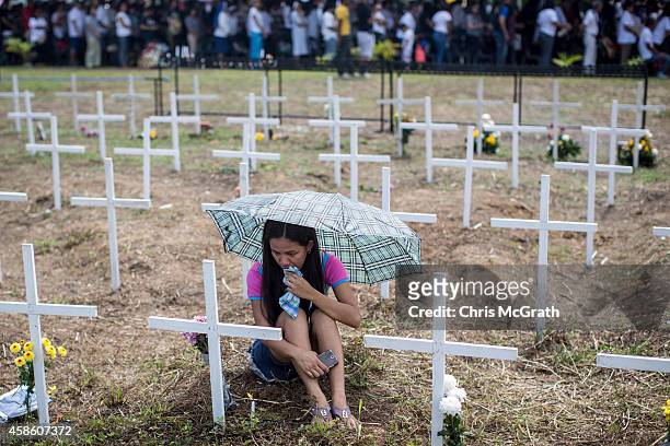 Woman cries at the cross of a loved one during a memorial service at the mass grave on the grounds of the Holy Cross Memorial Garden on November 8,...