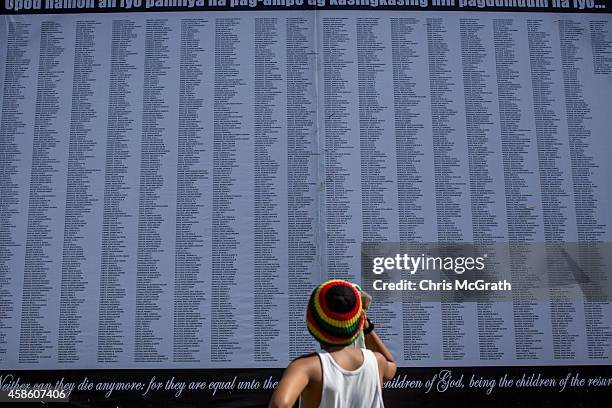 Young boy looks up at a board displaying names of victims during a memorial service at the mass grave on the grounds of the Holy Cross Memorial...