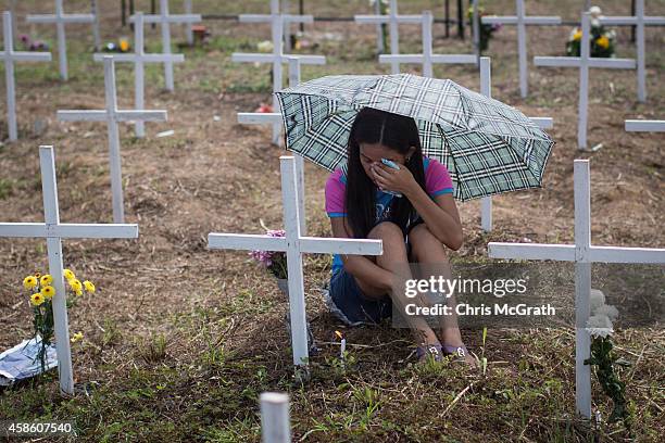 Woman cries at the cross of a loved one at the mass grave on the grounds of the Holy Cross Memorial Garden on November 8, 2014 in Tacloban, Leyte,...