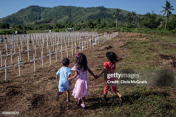 Children play amongst crosses at the mass grave on the grounds of the Holy Cross Memorial Garden on November 8, 2014 in Tacloban, Leyte, Philippines....