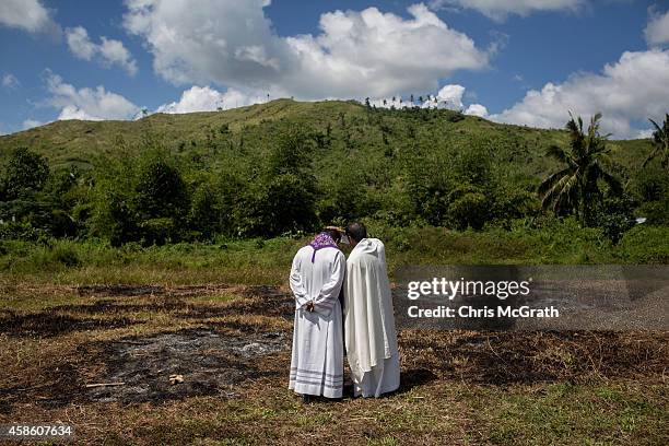 Parish priests conduct confession after blessing the graves of typhoon victims during a memorial service at the mass grave on the grounds of the Holy...