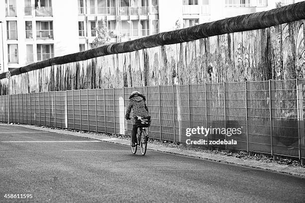 woman cycling along the ruins of berlin wall, germany - fall of the berlin wall stock pictures, royalty-free photos & images