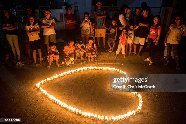 People gather on the street around candles shaped in a heart during the candlelight memorial on November 8, 2014 in Tacloban, Leyte, Philippines....