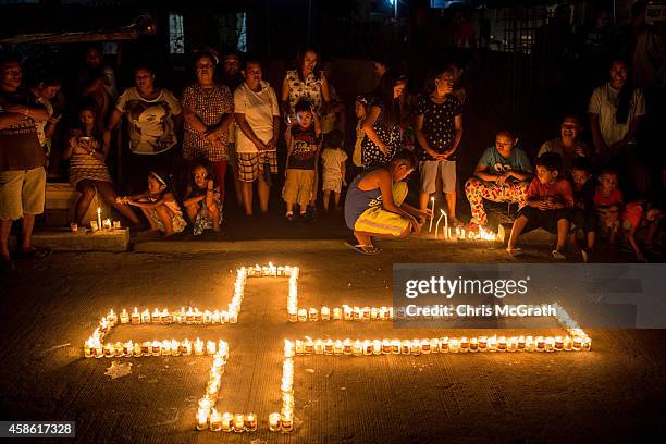 People gather on the street around candles shaped in a cross during the candlelight memorial on November 8, 2014 in Tacloban, Leyte, Philippines....