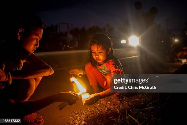 Young girl lights a candle on the roadside in San Jose during the candlelight memorial on November 8, 2014 in Tacloban, Leyte, Philippines. People...