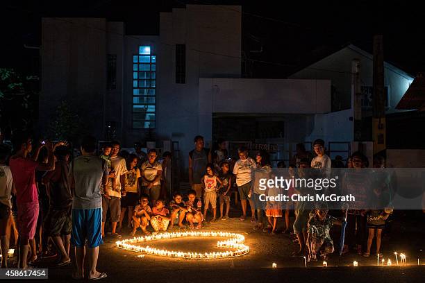 People gather on the street around candles shaped in a heart during the candlelight memorial on November 8, 2014 in Tacloban, Leyte, Philippines....