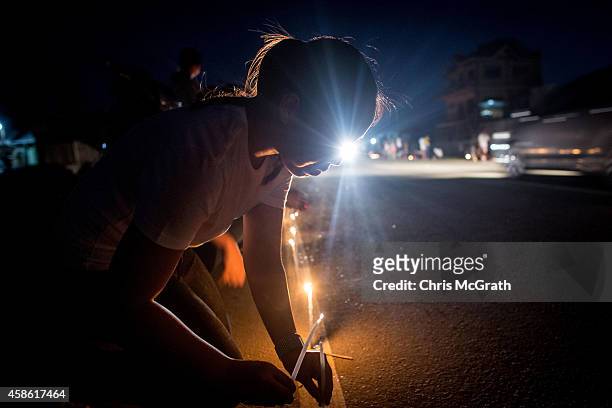 Woman lights a candle on the roadside in San Jose during the candlelight memorial on November 8, 2014 in Tacloban, Leyte, Philippines. People lined...