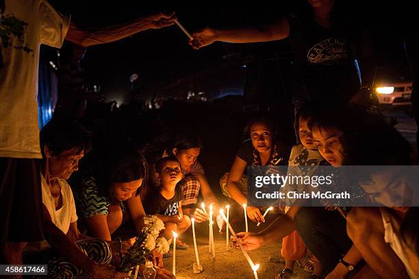 People sit around candles on the roadside in San Jose during the candlelight memorial on November 8, 2014 in Tacloban, Leyte, Philippines. People...