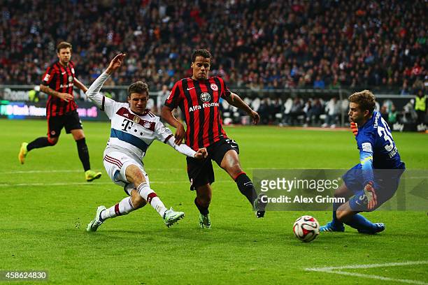 Thomas Mueller of Muenchen scores his team's third goal against Timothy Chandler and goalkeeper Felix Wiedwald of Frankfurt during the Bundesliga...