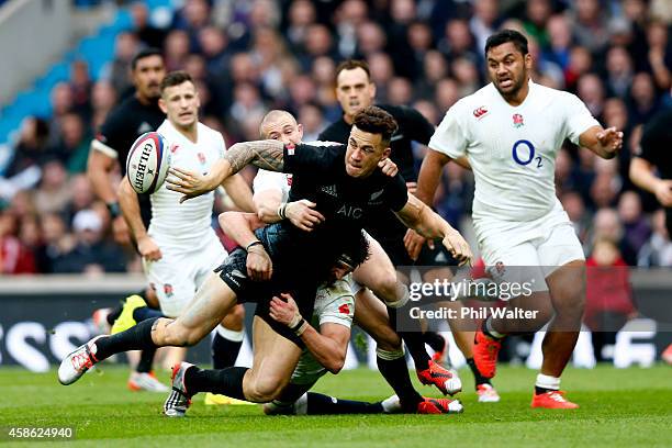 Sonny Bill Williams of New Zealand offloads the ball as he is tackled during the QBE International match between England and New Zealand at...