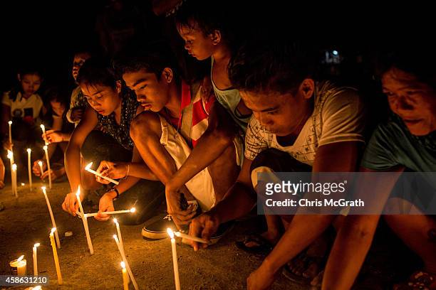 People sit around candles on the roadside in San Jose during the candlelight memorial on November 8, 2014 in Tacloban, Leyte, Philippines. People...