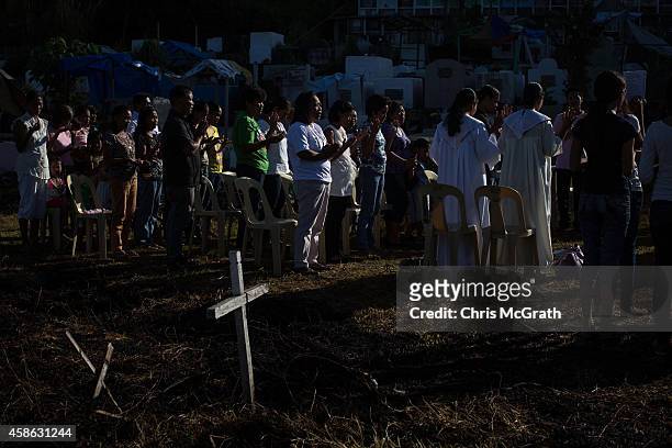 Friends and relatives of typhoon victims participate in a mass at Basper Cemetary, the original site of a mass grave which has now been moved to the...