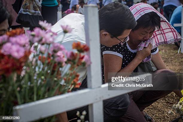 Woman is comforted by a friend as she cries at the cross of a loved one at the mass grave on the grounds of the Holy Cross Memorial Garden on...