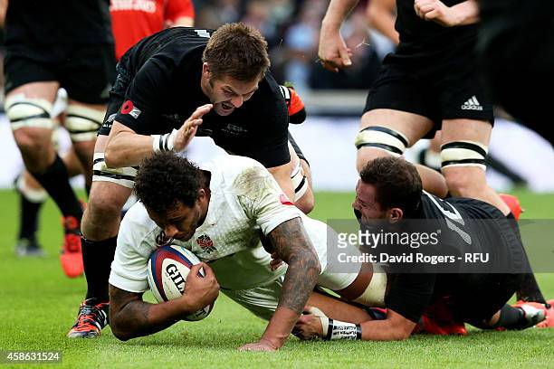 Dave Attwood of England is hauled down by Richie McCaw of New Zealand and Aaron Cruden of New Zealand during the QBE International match between...
