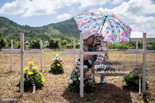 Willie Villarosa places candles at the grave of his sister and relatives and at the mass grave on the grounds of the Holy Cross Memorial Garden on...